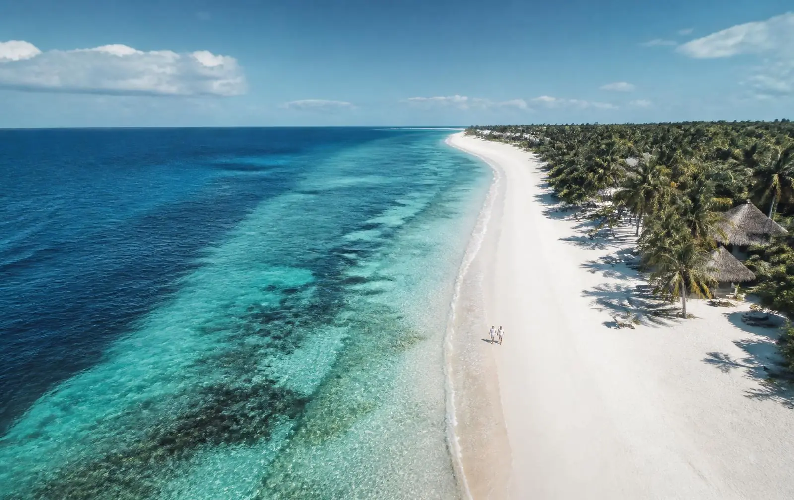 Long empty beach with turquoise reef water seen from above